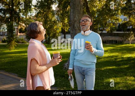 Felice coppia anziana che fa una pausa caffè passeggiando nel parco Foto Stock