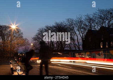 Una lunga esposizione di sentieri di luce creati dalle luci delle auto con sagome di persone vicino a una panchina sul Mill Road Bridge, Cambridge, Inghilterra, Regno Unito. Foto Stock