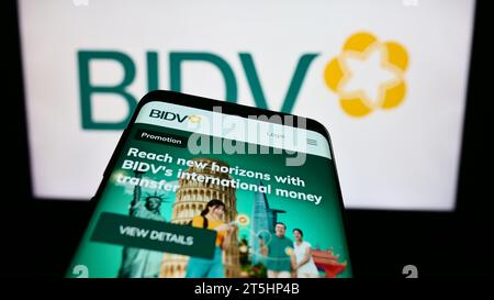 Smartphone con sito Web della Commercial Bank for Investment and Development of Vietnam davanti al logo. Mettere a fuoco in alto a sinistra sul display del telefono. Foto Stock