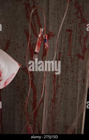 Un gocciolamento endovenoso nel sangue pesa sullo sfondo di una benda bianca, salute e medicina, macchie rosse su attrezzature mediche Foto Stock