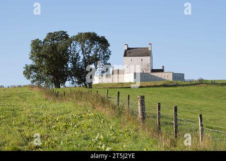 Scherma che conduce a una tribuna di alberi e al castello di Corgarff su una collina a Strathdon nelle Highlands scozzesi Foto Stock