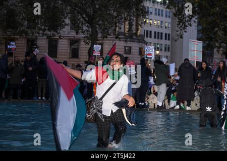 I manifestanti si arrampicano su una fontana a Trafalgar Sq durante una manifestazione pro-palestinese che chiede un cessate il fuoco dell'offensiva militare in corso a Gaza da parte dell'IS Foto Stock
