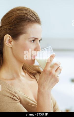 Giovane donna di bere latte in cucina moderna Foto Stock