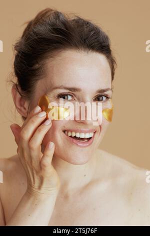 giovane donna felice con le cerchie oculari isolate sul beige. Foto Stock