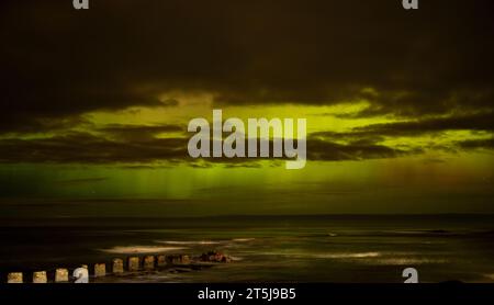 Green aurora attraverso le nuvole lungo la costa settentrionale della Scozia Foto Stock