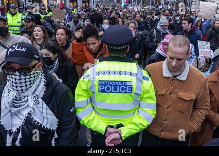 Londra, Regno Unito. 4 novembre 2023. Un ufficiale della polizia metropolitana monitora i manifestanti pro-palestinesi della Coalizione della Palestina libera che marciano attraverso il centro di Londra per chiedere un immediato cessate il fuoco a Gaza. Per il quarto fine settimana consecutivo in tutto il Regno Unito si sono svolte manifestazioni di solidarietà di massa palestinesi per chiedere la fine del bombardamento israeliano di Gaza. Crediti: Mark Kerrison/Alamy Live News Foto Stock