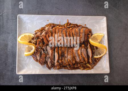 Vista dall'alto di un piatto quadrato bianco pieno di pesce dorato appena cucinato Foto Stock