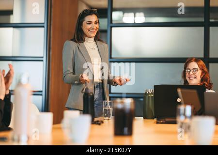 i professionisti aziendali si impegnano in una discussione dinamica e collaborativa in una sala riunioni luminosa. Il team diversificato, comprese le donne leader, condivide creatività Foto Stock