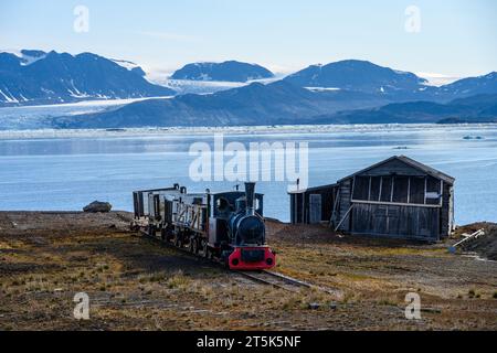 SVALBARD, NORVEGIA – 17 LUGLIO 2023: Resti storici dell'estrazione del carbone a NY Alesund, treno e binari con vista della baia sullo sfondo Foto Stock