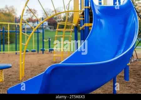 Tipico parco giochi per le scuole elementari non identificato con superficie anticaduta di sicurezza in fibra di legno Foto Stock