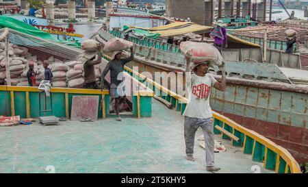Operaio che scarica cemento dalla barca, questa immagine è stata catturata il 29 maggio 2022, da Amen Bazar, Bangladesh Foto Stock