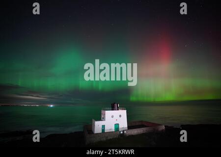 L'aurora boreale, nota anche come aurora boreale, appare sopra il faro di Bamburgh, nel Northumberland, sulla costa nord-orientale dell'Inghilterra. L'aurora potrebbe essere vista in tutto il Regno Unito domenica. Data foto: Domenica 5 novembre 2023. Foto Stock