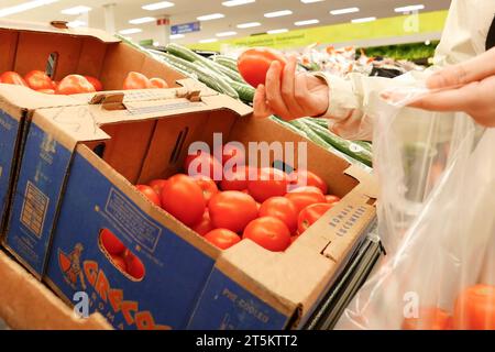 Donna che sceglie il pomodoro Roma all'interno di un negozio Walmart Foto Stock