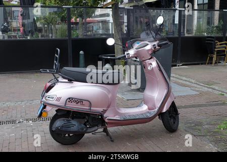 Assen, Paesi Bassi - 11 ottobre 2023 Uno scooter rosa AGM VX50i parcheggiato di fronte a un ristorante Foto Stock