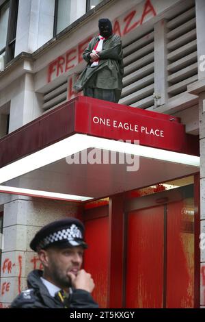 Londra, Regno Unito. 2 novembre 2023. Un attivista protesta contro il baldacchino sopra l'ingresso principale degli uffici, mentre gli agenti di polizia tengono d'occhio la parte sottostante. Gli attivisti di Palestine Action occupano e prendono di mira il gigante italiano dell'industria degli armamenti Leonardo nel loro quartier generale di Londra e li chiudono. Leonardo rifornisce Israele con jet da combattimento e armi attualmente in uso a Gaza. Palestine Action chiede che le compagnie di armamento che forniscono armi a Israele chiudano definitivamente. Hanno annunciato che le società che vendono armi alla forza di difesa israeliana e alle loro società partner saranno targ Foto Stock