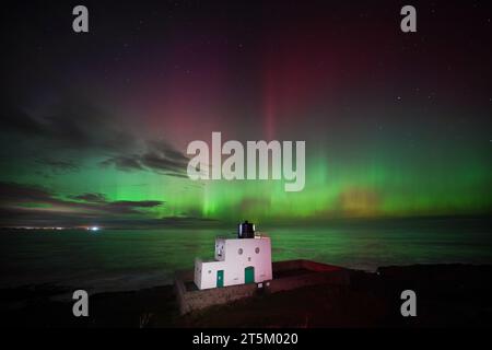 L'aurora boreale, nota anche come aurora boreale, appare sopra il faro di Bamburgh, nel Northumberland, sulla costa nord-orientale dell'Inghilterra. L'aurora potrebbe essere vista in tutto il Regno Unito domenica. Data foto: Domenica 5 novembre 2023. Foto Stock