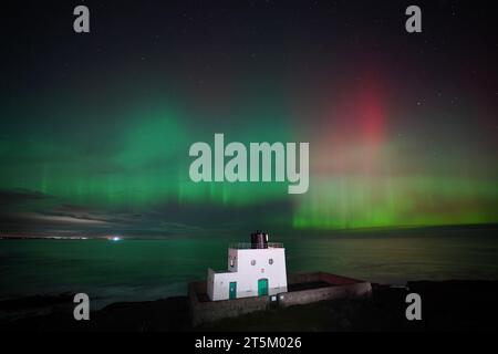 L'aurora boreale, nota anche come aurora boreale, appare sopra il faro di Bamburgh, nel Northumberland, sulla costa nord-orientale dell'Inghilterra. L'aurora potrebbe essere vista in tutto il Regno Unito domenica. Data foto: Domenica 5 novembre 2023. Foto Stock