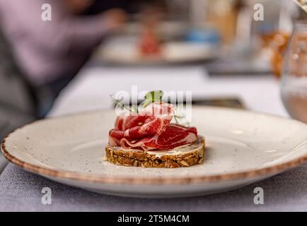 Prosciutto a fette sottili, elegantemente disposto su un pane Foto Stock