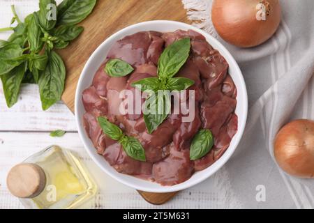 Ciotola con fegato di pollo crudo, basilico e cipolle su un tavolo di legno bianco, posata in piano Foto Stock