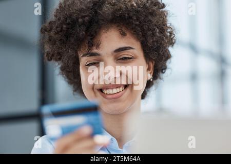 Una ragazza in un ufficio moderno paga gli acquisti su Internet utilizzando una carta di credito Foto Stock