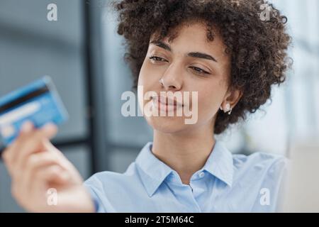 Una ragazza in un ufficio moderno paga gli acquisti su Internet utilizzando una carta di credito Foto Stock