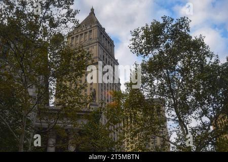 Un iconico edificio dell'orologio antico si erge alto, circondato da grattacieli moderni, sullo sfondo di un cielo americano blu vivo Foto Stock