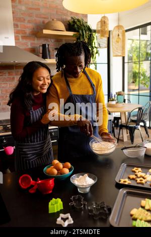 Allegri coppie che preparano biscotti natalizi mescolando l'impasto in cucina, spazio per copiare Foto Stock