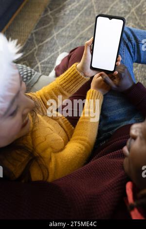 Felice coppia variegata nei cappelli di natale con videochiamata su smartphone, schermata spazio copia Foto Stock