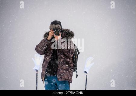 Uomo che tira una foto in una scena invernale con fiocchi di neve cadenti Foto Stock