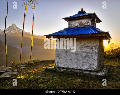 Un piccolo santuario religioso si trova su una terrazza erbosa di fronte a una montagna nella regione dell'Annapurna in Nepal. Foto Stock