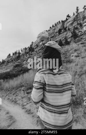 figlio di 4 anni sulle spalle di papà durante la passeggiata Foto Stock