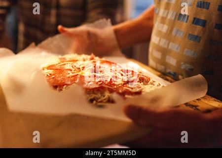 Primo piano di una mano che tiene una pizza fatta in casa Foto Stock