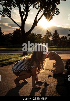 Simpatica bambina che bacia all'aperto il coniglio imbottito Foto Stock