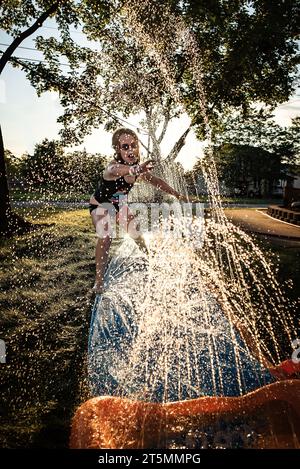 Giovane ragazza che gioca in acqua sullo scivolo Foto Stock