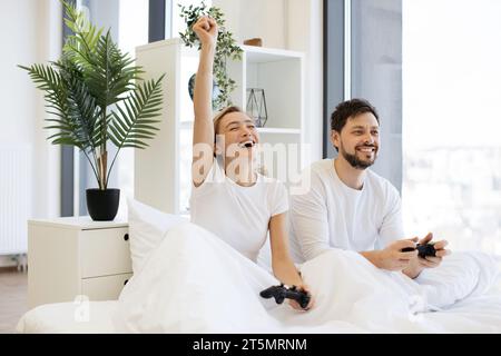 Vista frontale del caucasico che gioca ai videogiochi mentre si è seduti sotto coperta a casa. Foto Stock