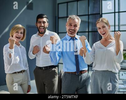 Un gruppo di giovani dipendenti che festeggia una vittoria davanti a un ufficio Foto Stock