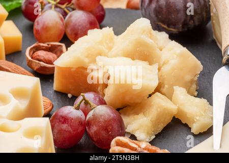 Varietà di formaggi a fette con frutta, menta, noci e taglierini. Un meraviglioso sfondo di formaggi per i vostri progetti. Foto Stock