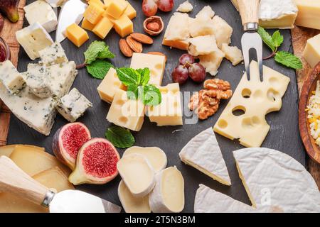 Varietà di formaggi a fette con frutta, menta, noci e taglierini. Un meraviglioso sfondo di formaggi per i vostri progetti. Foto Stock