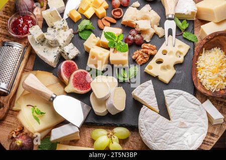 Varietà di formaggi a fette con frutta, menta, noci e taglierini. Un meraviglioso sfondo di formaggi per i vostri progetti. Foto Stock