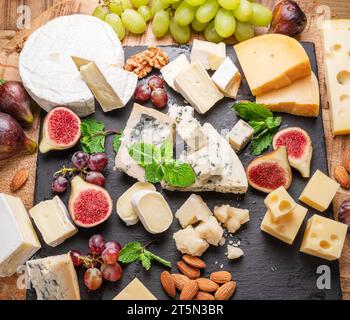 Varietà di formaggi a fette con frutta, menta, noci e taglierini. Un meraviglioso sfondo di formaggi per i vostri progetti. Foto Stock