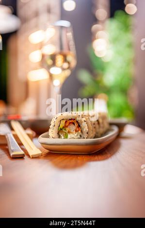 Sushi roll con formaggio cremoso, semi di sesamo e caviale di pesce volante verde su un piatto da vicino. Foto di alta qualità Foto Stock