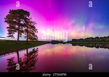 L'aurora boreale ( Aurora boreale ) vista sopra il bacino idrico di Whittle Dene nel Northumberland con riflessi nell'acqua Foto Stock