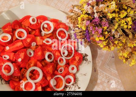 Pomodori e pere in un piatto di argilla beige. Pomodori rossi in un recipiente rustico. Vista dall'alto. Foto Stock