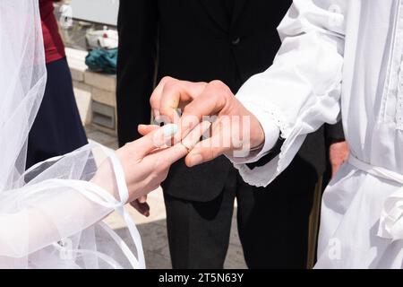 Una sposa estende la mano e il dito per ricevere l'anello acquistato dallo sposo durante una cerimonia di nozze ebraica. Foto Stock