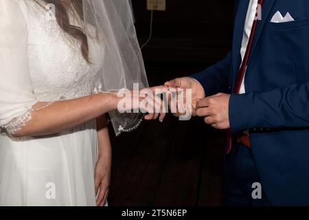 Una sposa estende la mano e il dito per ricevere l'anello acquistato dallo sposo durante una cerimonia di nozze ebraica. Foto Stock