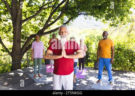 Gruppo eterogeneo di amici anziani che praticano yoga nel giardino soleggiato, spazio fotocopie Foto Stock