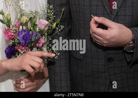 Uno sposo mostra l'anello che ha acquistato per la sua sposa e si prepara a metterlo sul dito durante la cerimonia di scambio o anelli di un matrimonio ebraico. Foto Stock