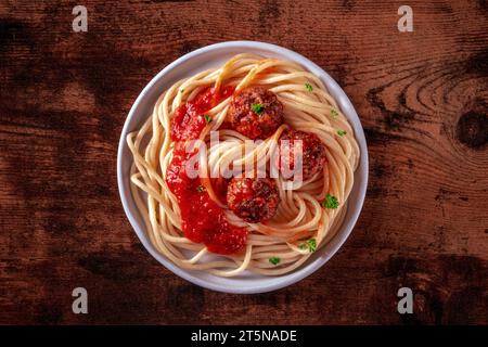 Polpette. Polpette di carne di manzo, con spaghetti, prezzemolo e salsa di pomodoro, su uno sfondo rustico di legno Foto Stock