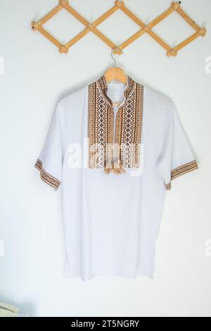 Camicia ricamata con abiti ucraini. Sfondo marrone beige e bianco con fili neri. Vyshyvanka simbolo dell'Ucraina. Ricamo con cuciture incrociate. Punto nazionale ucraino. Abbigliamento tradizionale. Foto Stock