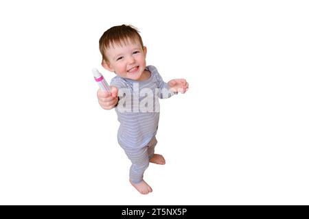 Il bambino ha aperto il cassetto con pillole e unguento, isolato su sfondo bianco. Bambino che tiene la crema in piedi nel salotto di casa. Ki Foto Stock